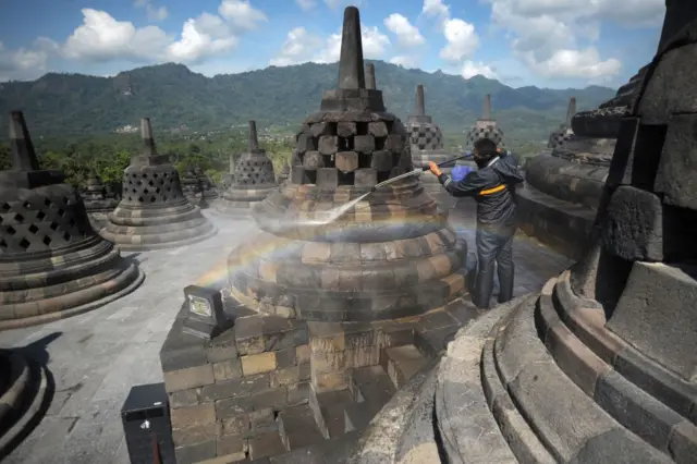 Seorang pekerja membersihkan abu vulkanik dari stupa di candi Borobudur di Kabupaten Magelang pada 22 Juni 2020,