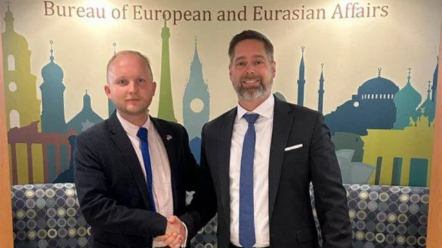 Одним из контактов белорусской оппозиции (слева Денис Кучинский) в США стал представитель Госдепартамента Кристофер Смит (справа). Именно он как эксперт по Восточной Европе начал контакты с официальным Минском. Фото сделано в Вашингтоне. Оба в темных костюмах и синих галстуках жмут друг другу руки и позируют на фоне надписи: "Бюро европейских и евразийских дел"