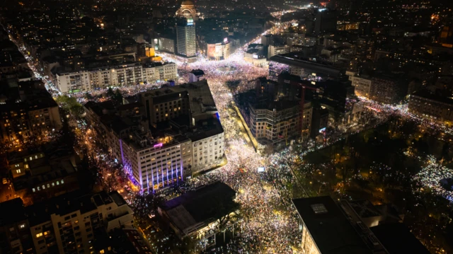 Fotografia aérea mostra manifestantes segurando seus celulares para iluminar o céu noturno em memória daqueles que morreram no desastre do telhado de Novi Sad