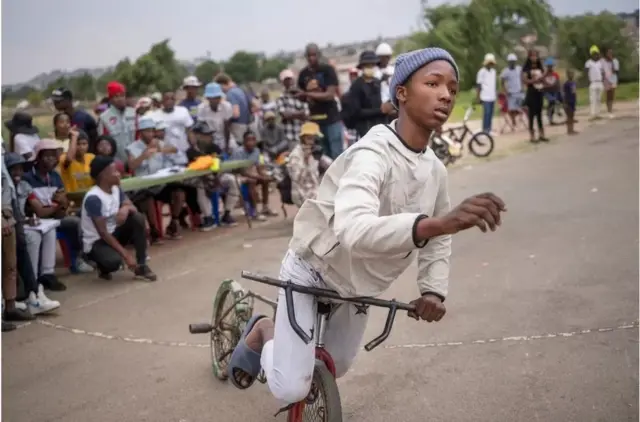A young South African man pulls a stunt at an event run by the Soweto Street Fighters crew on Saturday, in which hundreds of young men from the township gather to compete for who puts on the best performance, including the best looking bike.