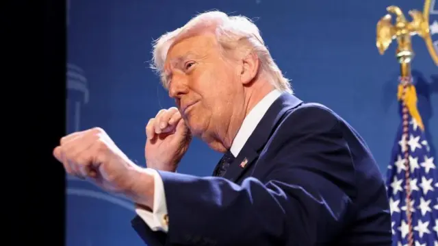 星条旗などを背に、笑顔を浮かべ、両手を軽く握って前後に動かしている様子のトランプ氏