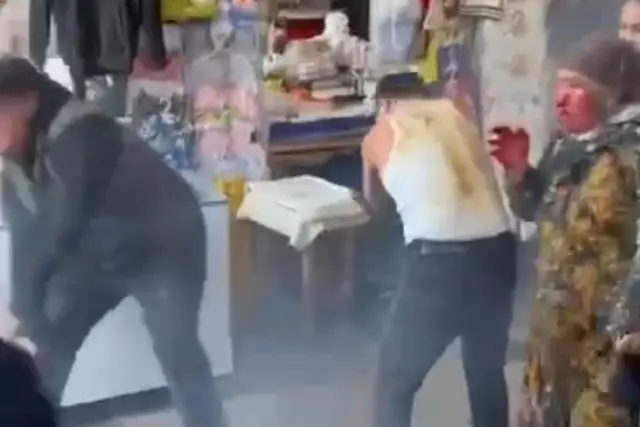 Ikkita erkak o'zlarini himoyalab yuzlarini tozalashyapti, o'ngda bir ayol qo'li va yuzi qonagan shoikm holatda turibdi