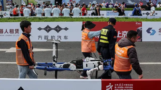 19 апреля 2026 года в Пекине (Китай) сотрудники поднимают гуманоидного робота, упавшего после финиша второго Пекинского полумарафона E-Town и полумарафона гуманоидных роботов