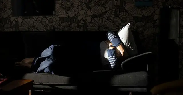 Dalam ilustrasi foto ini, seorang wanita di sofa menutupi wajahnya dengan bantal pada 6 April 2020 di Bonn, Jerman. 