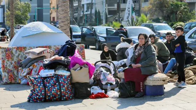 žene i muškarci sa stvarima sede vani 