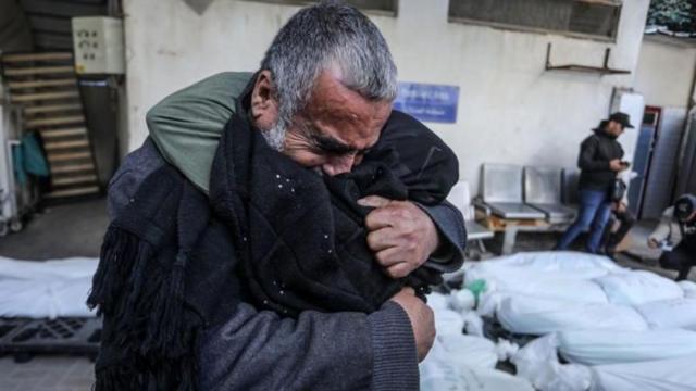 Idoso abraça criança após bombardeio na faixa de Gaza