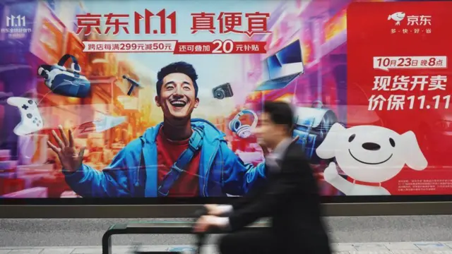 A man rides past a billboard promoting Singles Day in Hangzhou, China, om 11 November 2023
