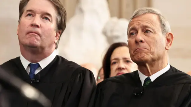 O juiz da Suprema Corte dos EUA, Brett Kavanaugh (esquerda), e o Presidente da Suprema Corte dos EUA, John Roberts, ouvem o discurso do Presidente dos EUA, Donald Trump, durante as cerimônias de posse na Rotunda do Capitólio dos EUA, em 20 de janeiro de 2025, em Washington, DC