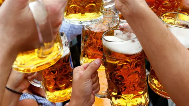 Osoby wznoszą toast piwem pierwszego dnia Oktoberfest w Monachium
