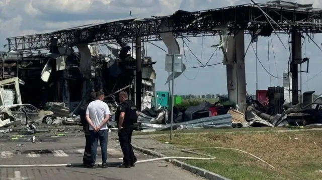 Люди стоять біля знищеної АЗС