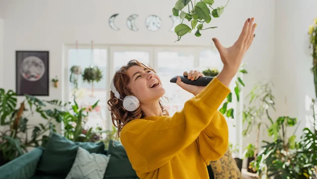 umugore ariko aririmba . azamuye hejuru ukuboko, inyuma haboneka amashurwe