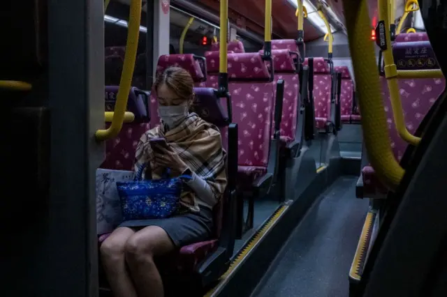 2022年11月，一名女子坐在巴士里面，正看着手机。