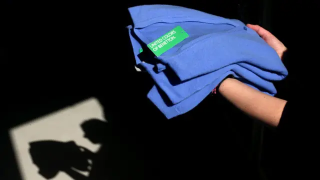 Chica sosteniendo suéters de Benetton