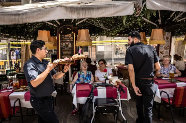 La terrasse d'un bar et deux serveurs.