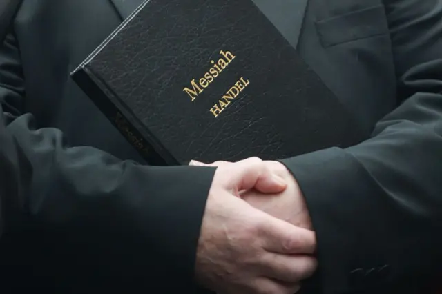 Un cantante sostiene una partitura del Mesías.