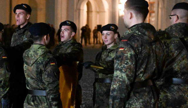 Yemin töreni yapan kamuflajlı askerler. Bir kadın asker görünüyor aralarından