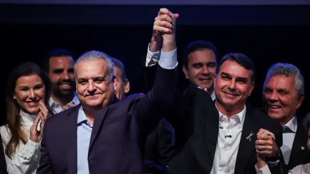 Alfredo Gaspar e Flávio Bolsonaro de mãos dadas e erguidas