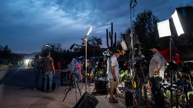Los equipos de cámaras se instalan cerca de la casa de Nancy Guthrie, el cielo está oscuro y el sol casi se pone.
