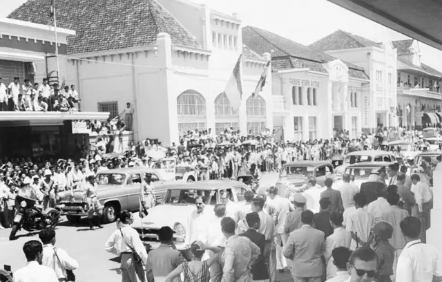 Warga Kota Bandung dan sekitarnya menyaksikan iring-iringan kendaraan yang membawa para kepala negara peserta Konferensi Asia-Afrika, pada 1955.