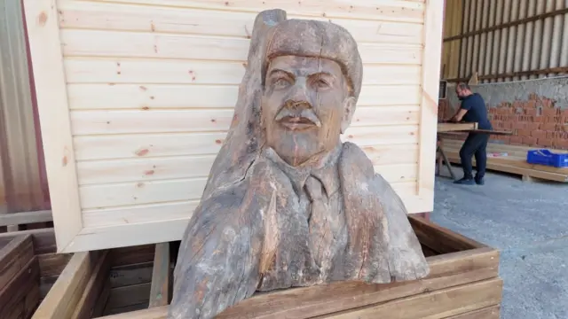 Ahşap Lenin büstü. Büstte Lenin şapkası, kabanı ve kravatıyla görülüyor. 