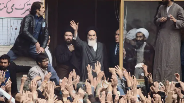 Ayatollah Humeyni, coşkulu destekçilerinden oluşan kalabalığa el sallıyor. Destekçileri de karşılık olarak el sallıyor.