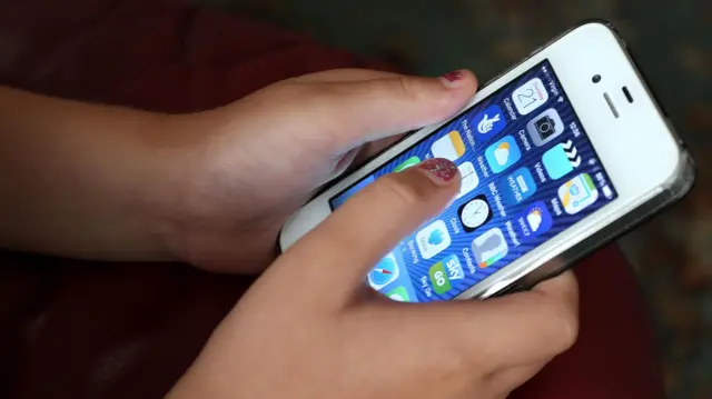 طفل يستخدم هاتف آيفون ذكي من آبل