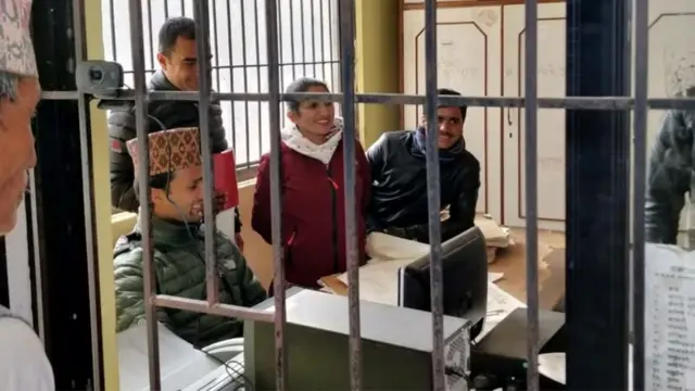 भरतपुरस्थित मालपोत कार्यालयका कर्मचारीलाई झ्यालबाहिरबाट हेर्दै एक सेवाग्राही