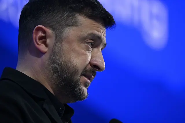 Zelenskiy profilden görünüyor. Sadece kafasını görüyoruz, arkada mavi bir fon var.