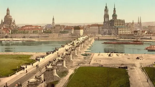 Imagen de Dresde en 1900, con un puente sobre un río y grandes edificios al fondo. 