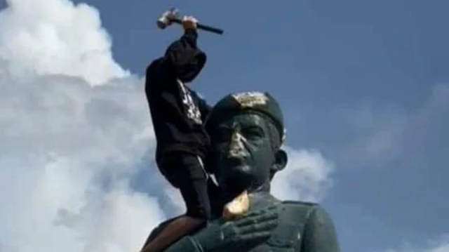 Un hombre sobre la estatua de Chávez