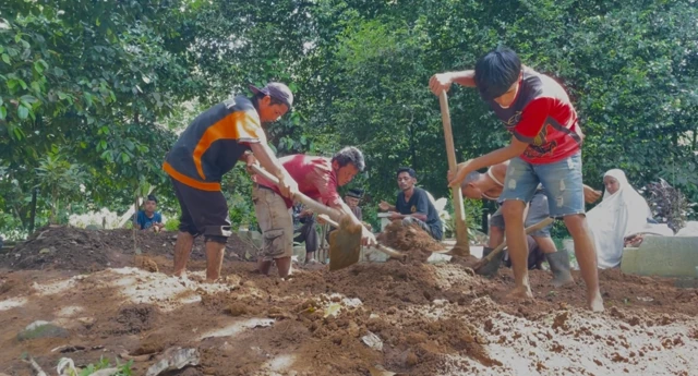 Beberapa pria menguruk tanah dengan cangkul untuk memakamkan jenazah warga yang meninggal akibat banjir bandang di Sumbar