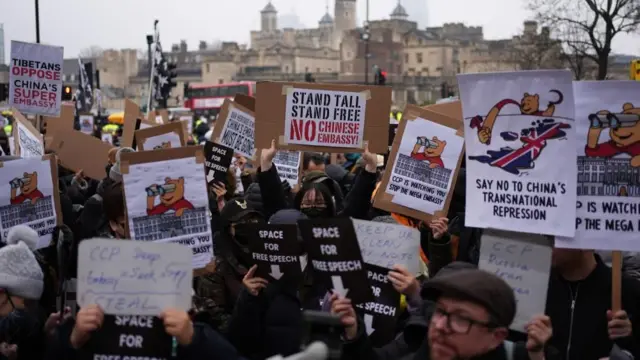 伦敦前皇家铸币厂外一群示威者举起反对中国“超级大使馆”的标语牌，包括指控中国监视在英异见人士、实施跨境镇压等（8/2/2025）