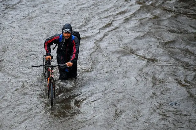 মুম্বাইয়ের বান্দ্রায় জলের ভেতর দিয়ে বাইসাইকেল ঠেলে অফিস যাওয়ার চেষ্টায় একজন নিত্যযাত্রী