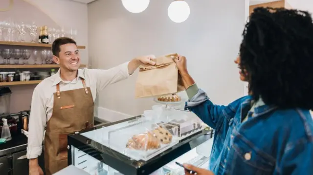 Une femme achète de la nourriture à un barista dans un café.