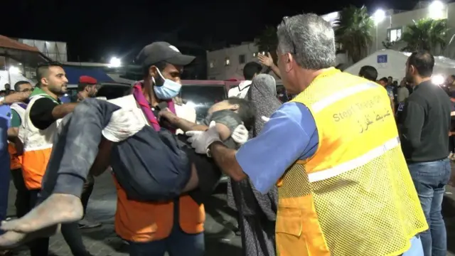 Um paramédico carrega uma criança nos braçoscasino 440uma ambulância para o hospital