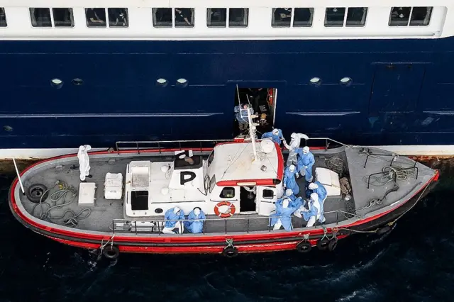 Petugas kesehatan memindahkan penumpang dari MV Hondius.