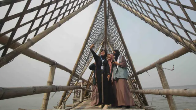 Pengunjung berswafoto saat berwisata di Ekowisata Mangrove Wonorejo, Surabaya, Jawa Timur, Sabtu (08/04)