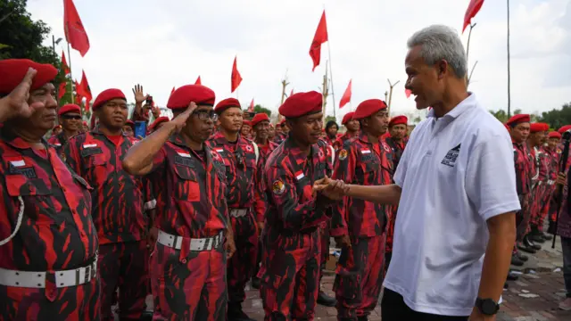 Capres nomor urut 3 Ganjar Pranowo (kanan) menyalami peserta saat menghadiri Apel Satgas PDIP DPC Kota Surakarta di Taman Sunan Jogo Kali, Pucang Sawit, Surakarta, Jawa Tengah, Minggu (24/12/2023).