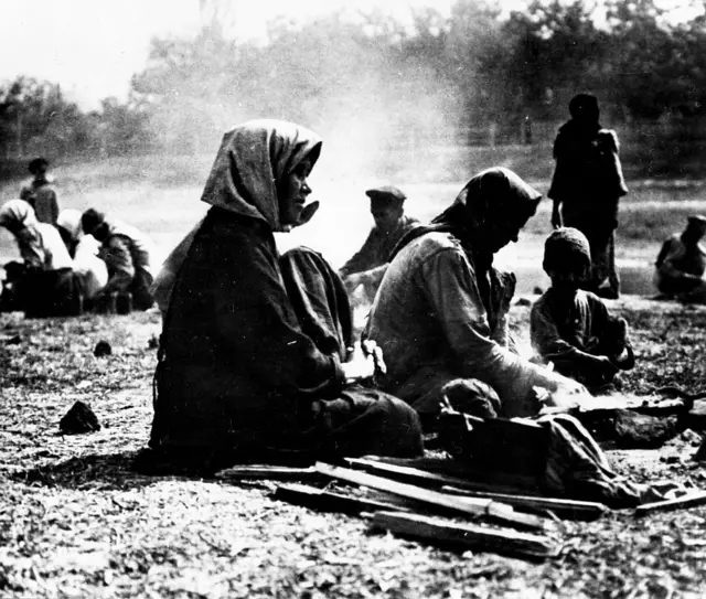 Siyah beyaz fotoğraf: yerde oturan kadın ve çocuklar