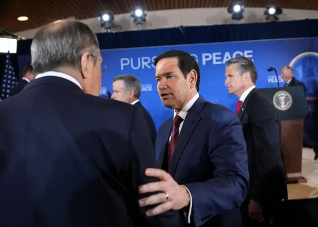 Лавров стоит спиной к камере, Рубио говорит ему что-то, касаясь рукой его плеча