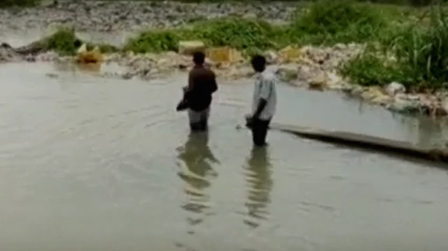 Ọkunrin meji n rin ninu omi nibi iṣẹlẹ omiyale to waye ni ipinlẹ Ogun 