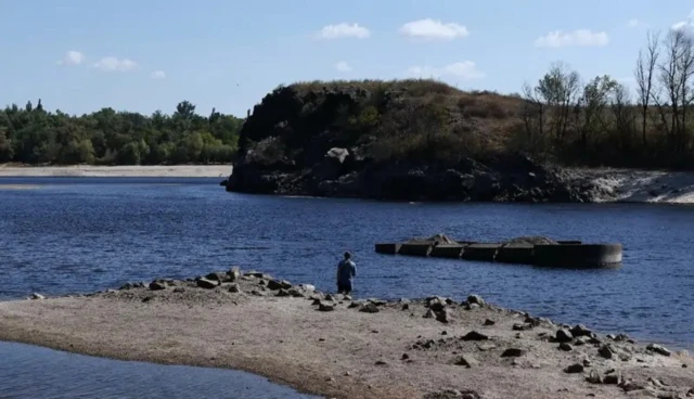 Человек стоит на берегу реки спиной к фотографу