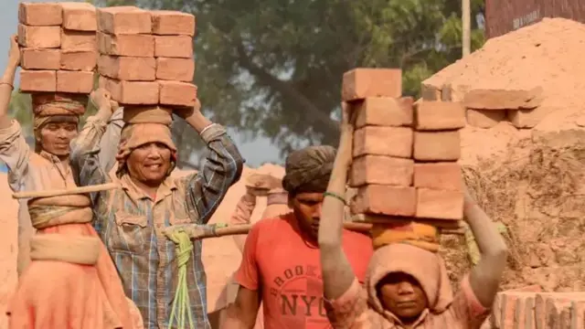 দুই জন নারী ও দুই জন পুরুষ মাথায় ইট বহন করছেন, প্রতীকী ছবি