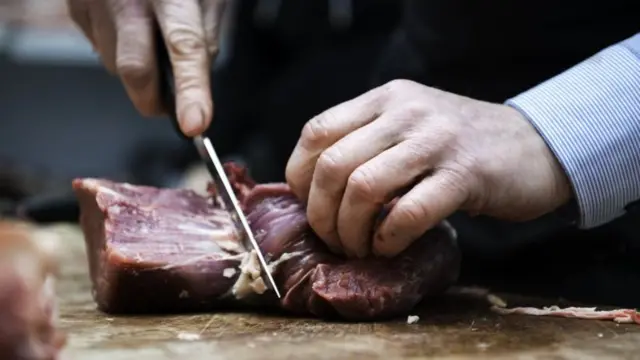 Mãofoguete apostas onlinealguém cortando carne sobre uma tábua