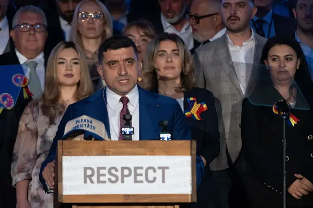 المررشح الرئاسي جورج سيميون، زعيم حزب "التحالف من أجل وحدة الرومانيين" اليميني، يخطب وسط أنصاره وأمامه ميكروفون.