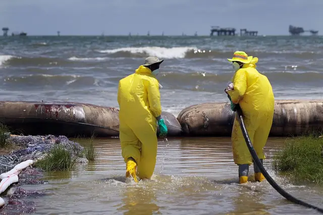 Hombres limpian una playa tras el Deepwater Horizon