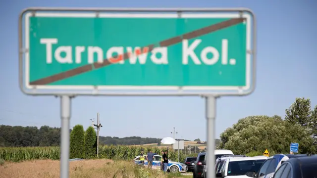 „Tarnawa Kolonia” feliratú közúti tábla és autók annak a helyszínnek a közelében, ahol feltételezések szerint orosz manőverező robotrepülőgép zuhant le, miután megsértette a lengyel légteret.