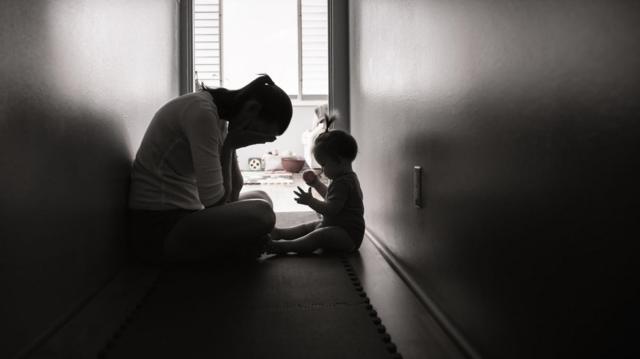 Mãe com a mão cobrindo o rostoxbet 99sinalxbet 99cansaço ao lado da filha