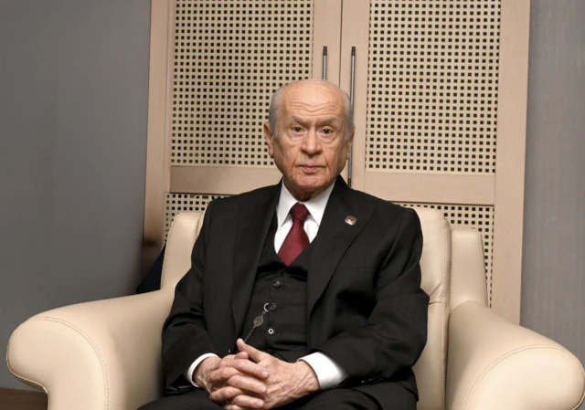 Devlet Bahçeli bir deri koltukta oturuyor.