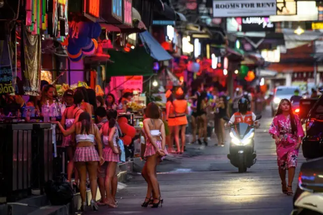 Employees wait for customers outside a bar on a street in Pattaya on September 1, 2020. 